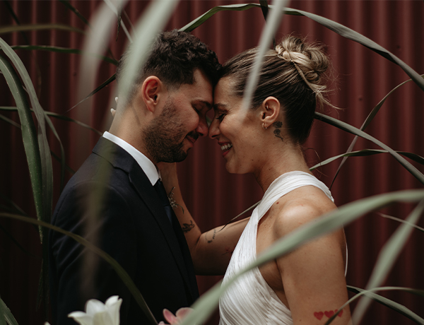 Novios abrazados y sonriendo entre plantas, foto real de boda de POGO Eventos